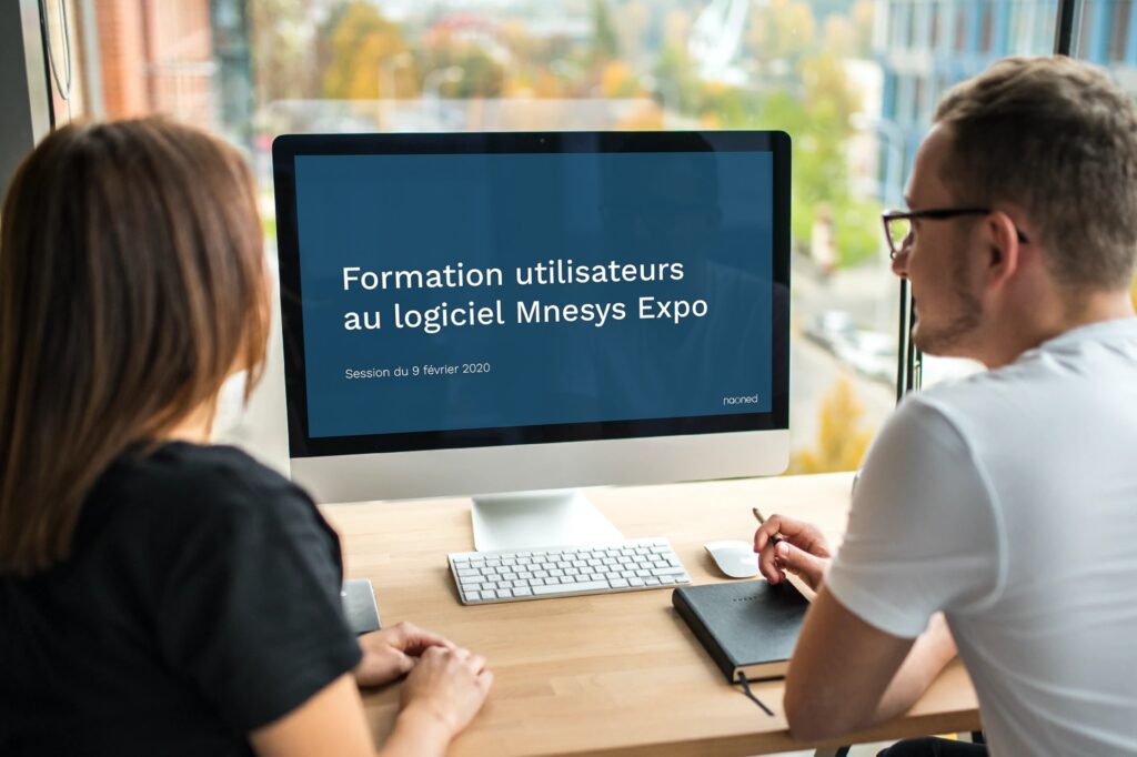 2 personnes devant un écran pour la formation sur Mnesys Expo