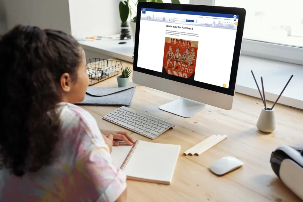 Jeune fille devant son PC sur la page Jouez avec les Archives des AM de Lille